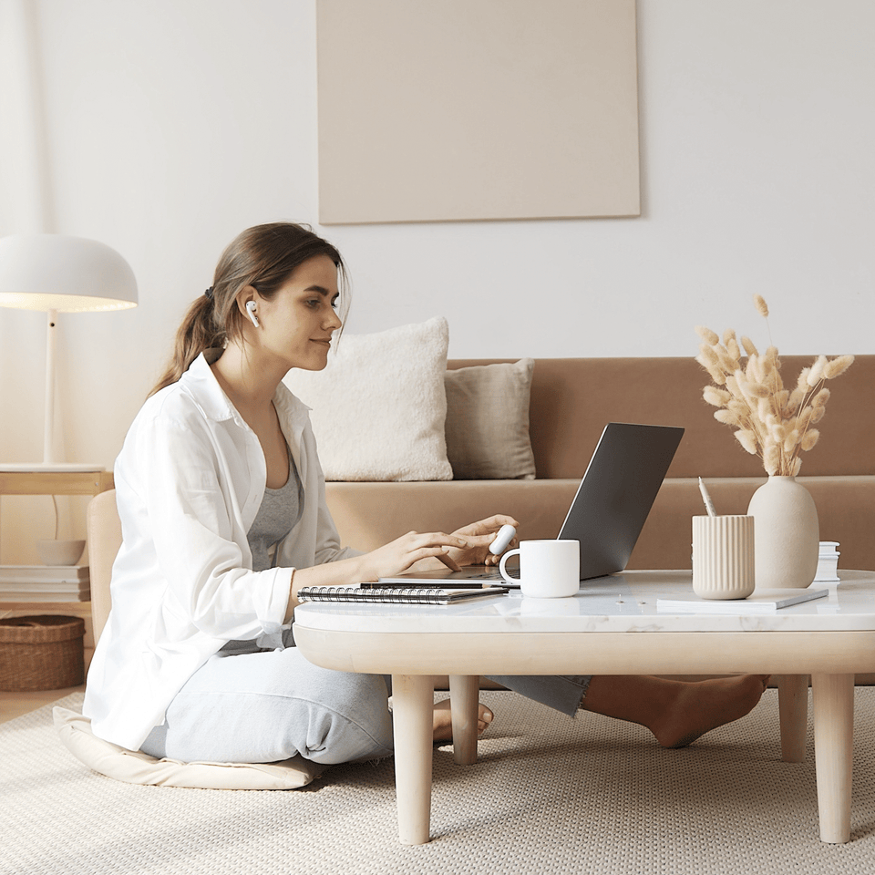 Eine junge Frau lernt konzentriert mit einem Laptop am Couchtisch