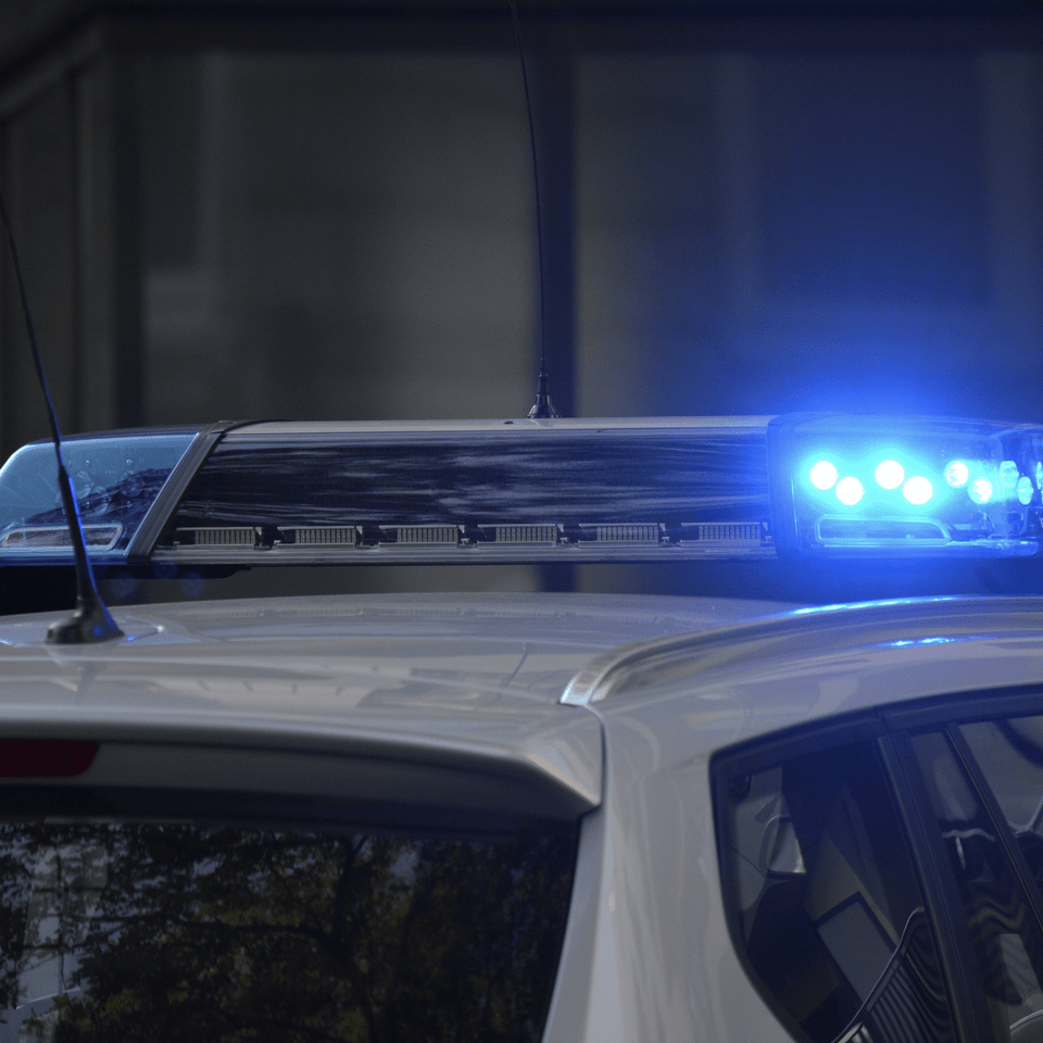 Eingeschaltetes Blaulicht auf dem Dach eines weißen Polizeiwagens