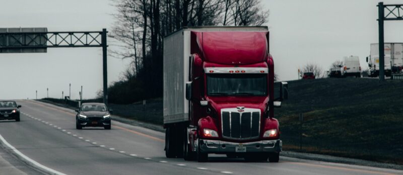 Ein roter Lkw auf einer Straße zur Veranschaulichung des Berufs als Berufskraftfahrer