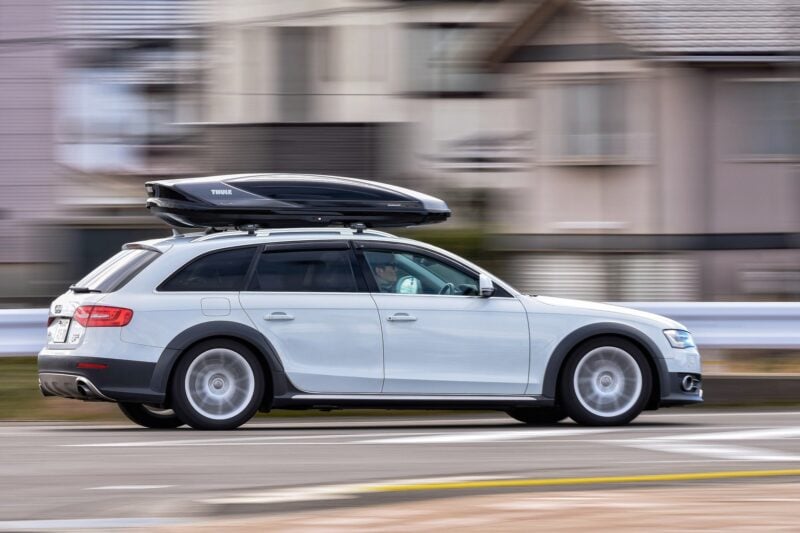 Ein weißer Audi Kombi mit Dachbox in schneller Fahrt auf einer Straße