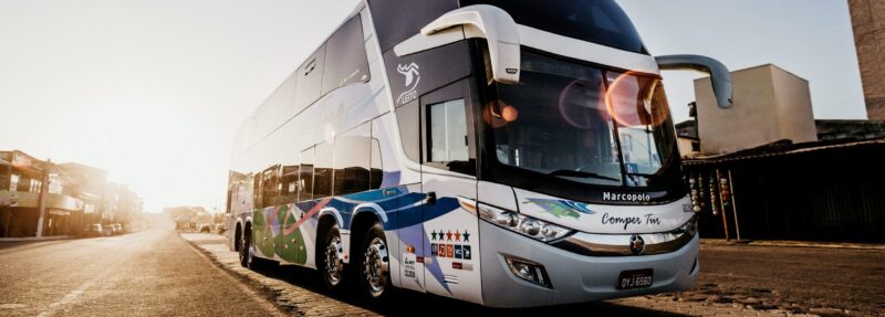 Moderner Doppeldecker-Reisebus auf einer Straße bei Sonnenuntergang als Symbol für den Beruf des Busfahrers