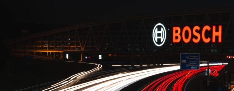 Beleuchtetes Bosch-Logo an einem Gebäude bei Nacht über einer Autobahn