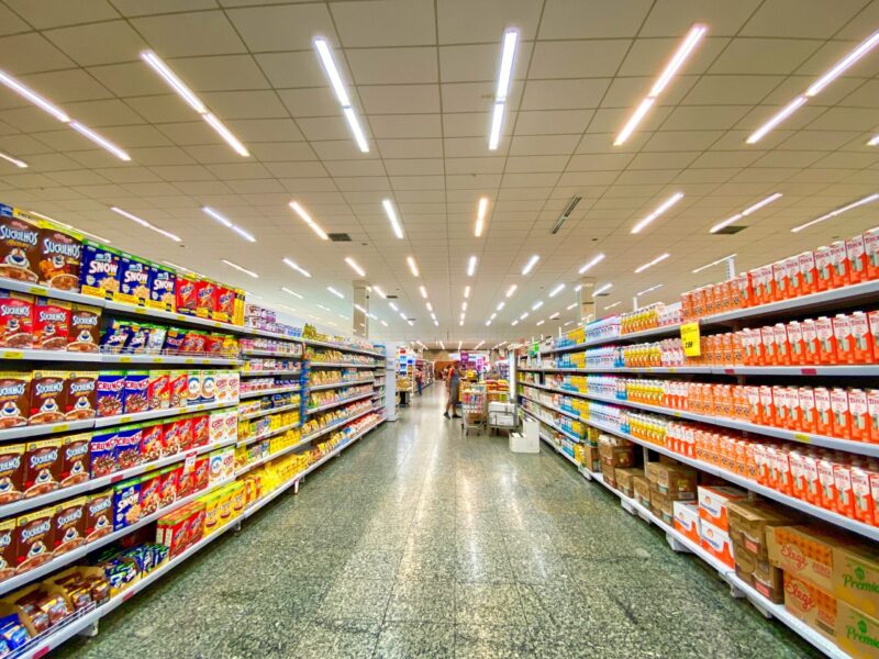 Gut gefüllte Regale in einem Supermarkt-Gang als typisches Arbeitsumfeld im Einzelhandel