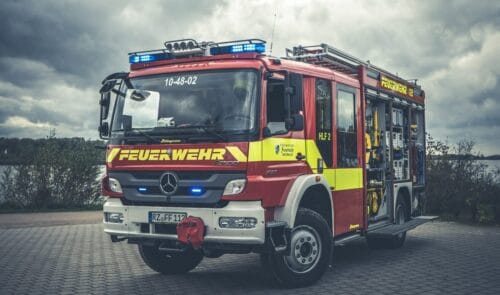 Ein rotes Feuerwehrfahrzeug mit eingeschaltetem Blaulicht zur Veranschaulichung der Feuerwehr-Karriere