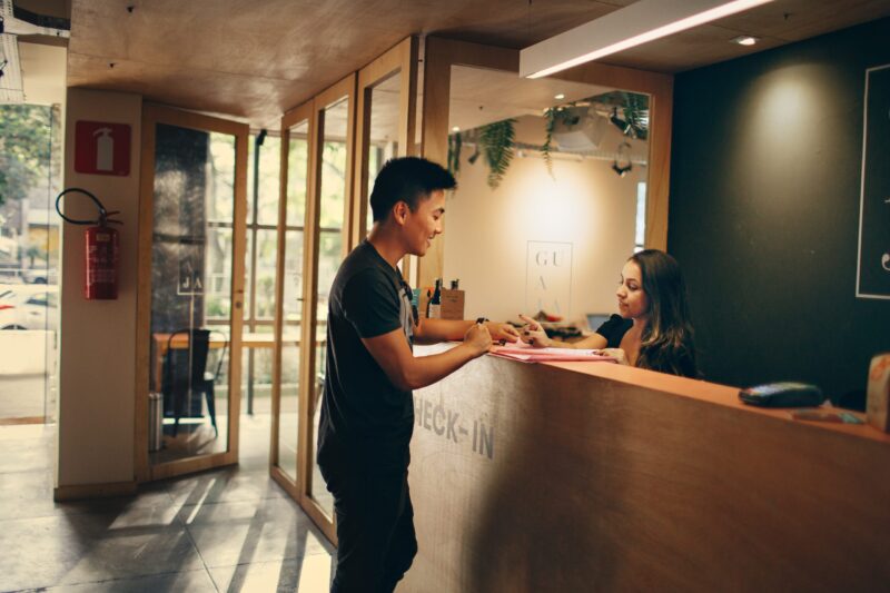 Eine Hotelfachkraft im Gespräch mit einem Gast an der Rezeption eines Hotels