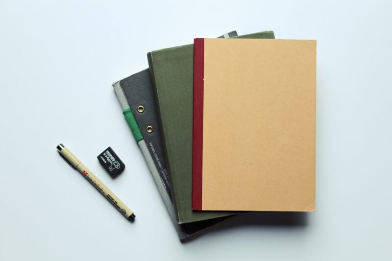 Stapel aus Notizbüchern und Mappen mit Stift als Symbol für eine Bewerbungsmappe