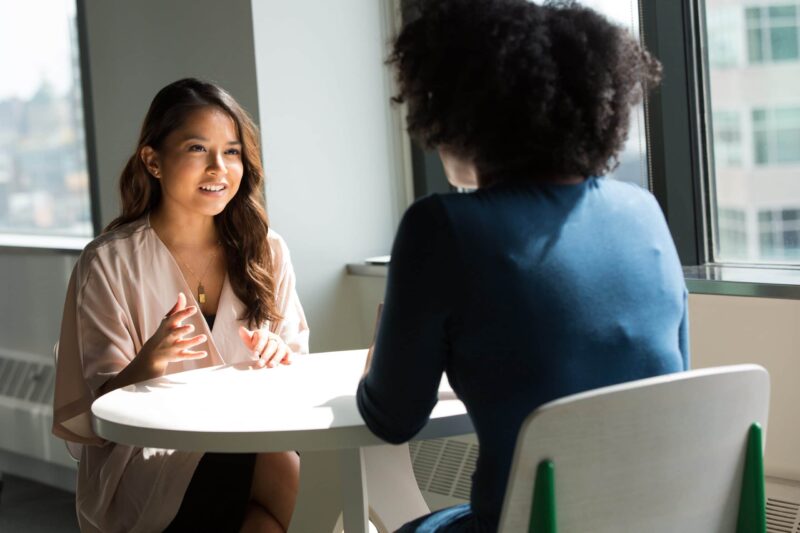 Zwei Frauen im Gespräch an einem Tisch zur Veranschaulichung eines Vorstellungsgesprächs