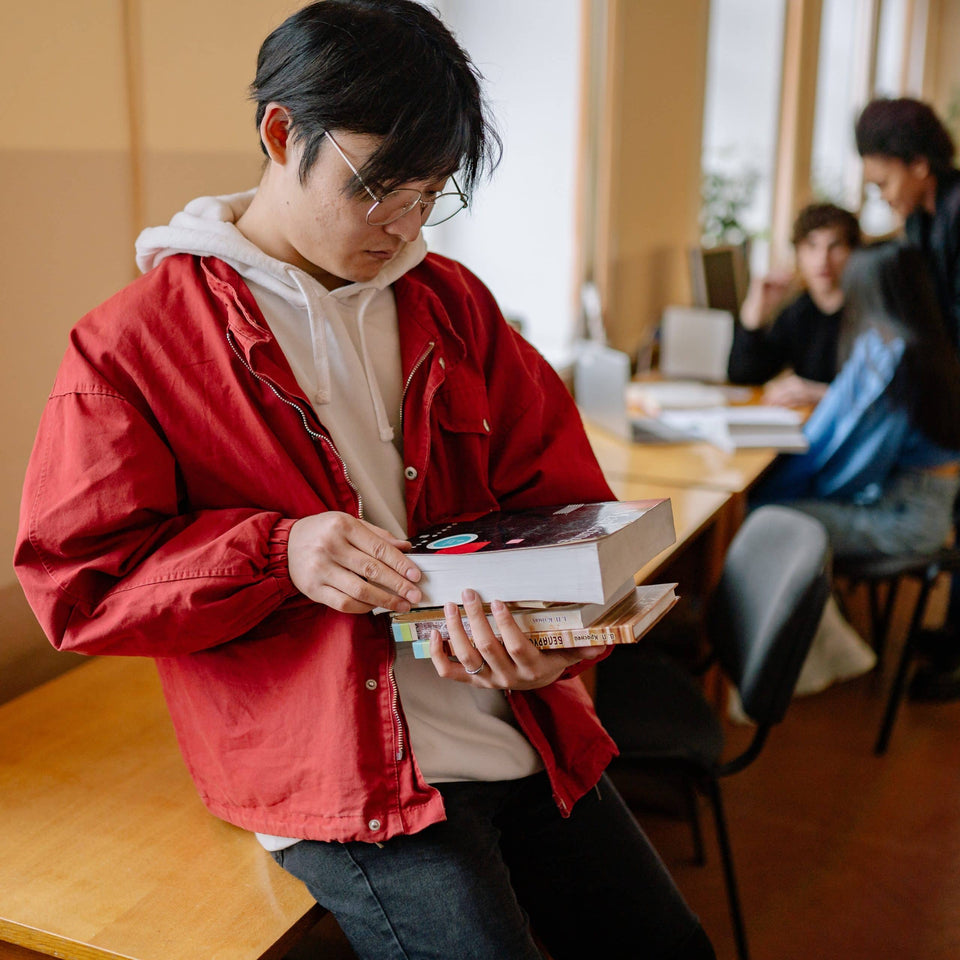 Ein junger Mann mit Brille lernt mit Büchern in einem Klassenzimmer