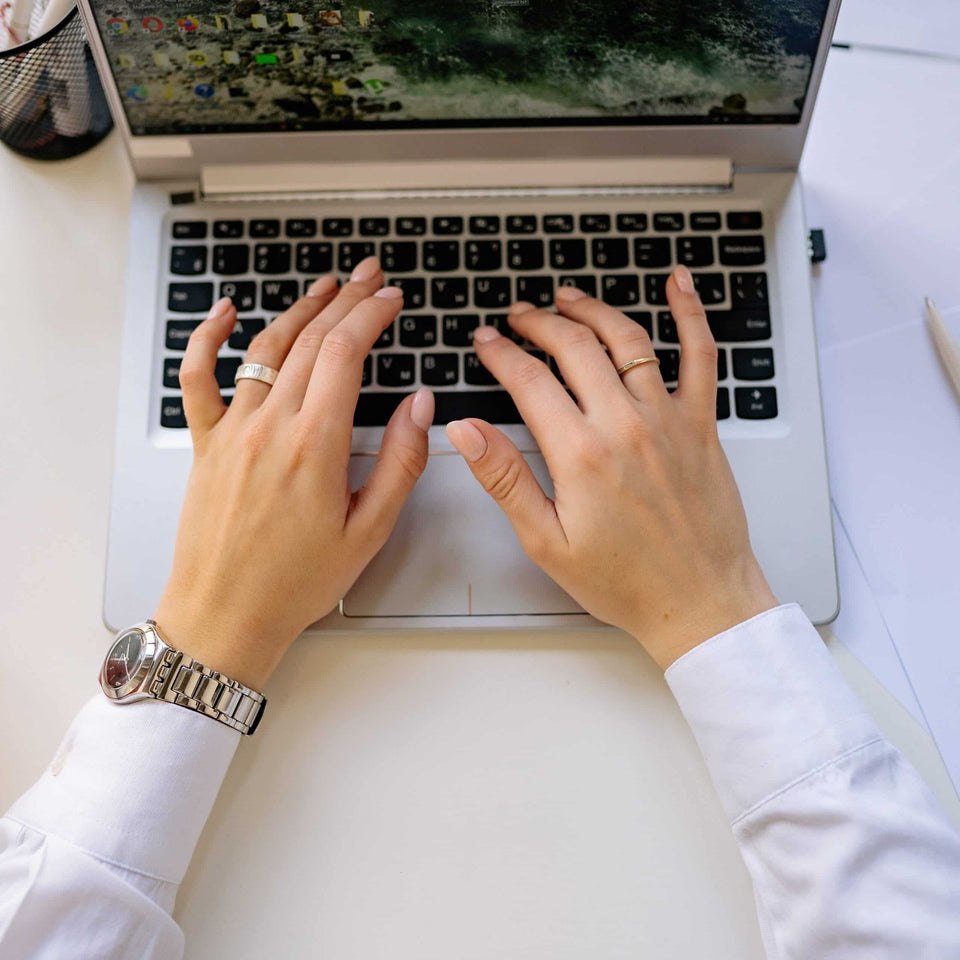 Hände einer Person beim Schreiben einer E-Mail auf einer Laptop-Tastatur