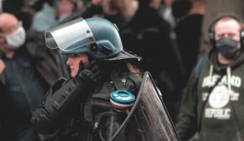Einsatzkraft in Schutzausrüstung mit Helm und Schild bei einer Demonstration