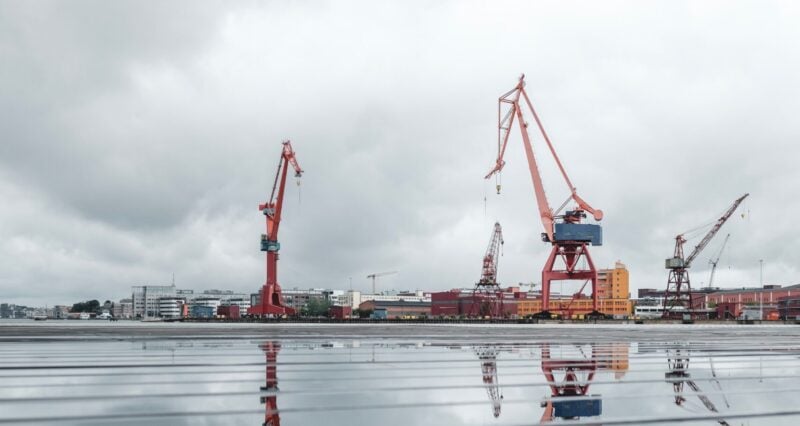 Große rote Hafenkräne an einem Kai zur Veranschaulichung des Arbeitsumfelds von Kranführern