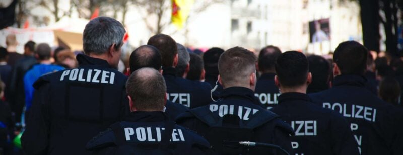 Mehrere Polizisten in dunkler Uniform mit der Aufschrift Polizei von hinten