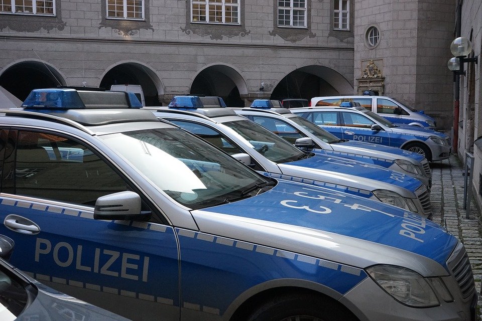 Mehrere blau-silberne Polizeiautos in einer Reihe geparkt vor einem historischen Gebäude
