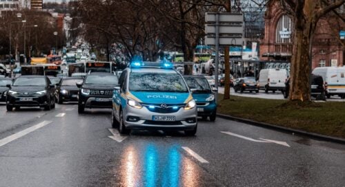Ein deutscher Polizeistreifenwagen mit eingeschaltetem Blaulicht im fließenden Stadtverkehr