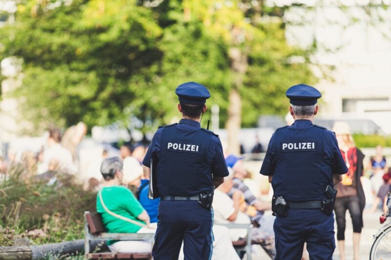Zwei Polizisten in blauer Uniform von hinten im Einsatz im öffentlichen Raum