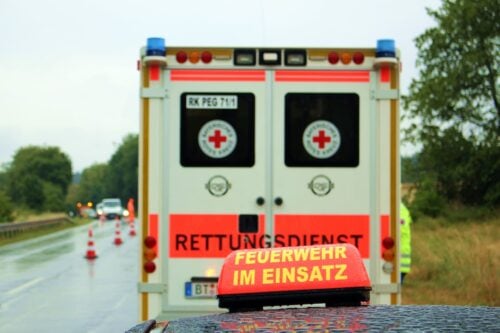 Rettungswagen und ein Schild mit der Aufschrift Feuerwehr im Einsatz auf einer Straße
