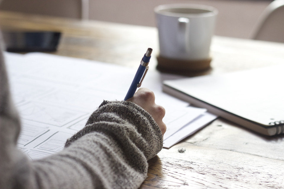 Eine Person schreibt mit einem Stift auf Papier, um für einen schriftlichen Test zu lernen