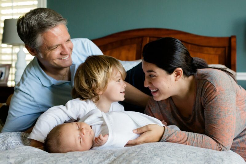 Eine glückliche Familie mit einem Neugeborenen und einem Kleinkind im Bett