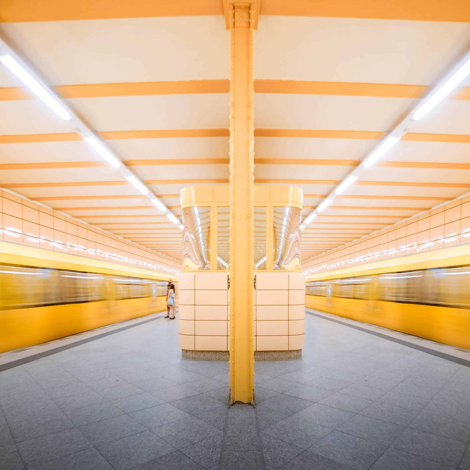 Gelbe U-Bahnen an einem symmetrisch gestalteten Bahnsteig als Symbol für den öffentlichen Schienenverkehr