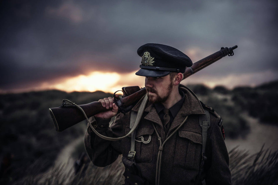 Soldat in Uniform mit einem Gewehr über der Schulter vor einem bewölkten Abendhimmel